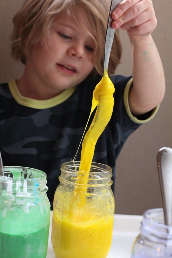 Girl pulling yellow rainbow slime out of a jar.