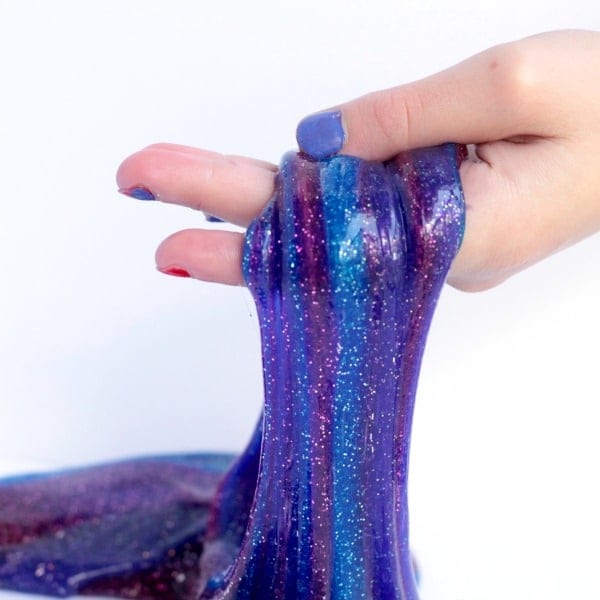 Sparkling slime galaxy stretched in hand.