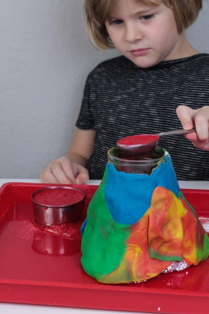 Girl pouring vinegar into baking soda and vinegar volcano